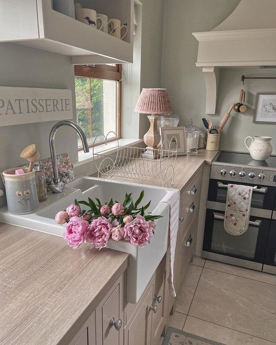 a kitchen with pink flowers on the counter top and sink in front of an oven