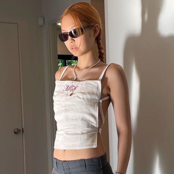 a young woman wearing sunglasses standing in front of a mirror with her hands on her hips