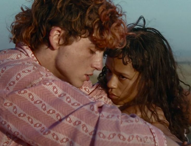 a young man and woman embracing each other in the middle of an open desert area