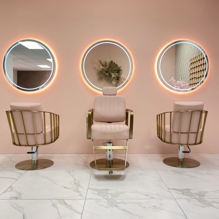 three round mirrors on the wall above two chairs in front of each other with circular lights around them