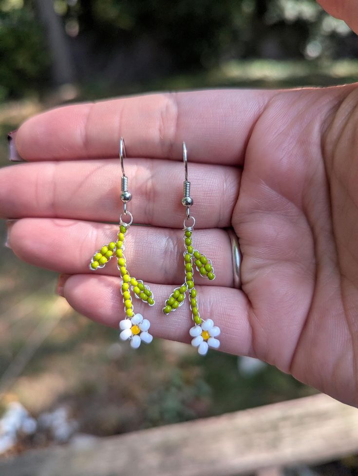 a person is holding out their hand with some small flowers on it's ear