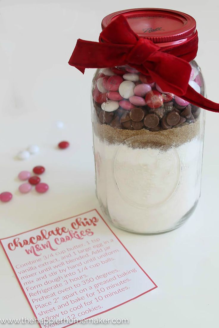 a jar filled with lots of candy sitting on top of a table next to a red ribbon