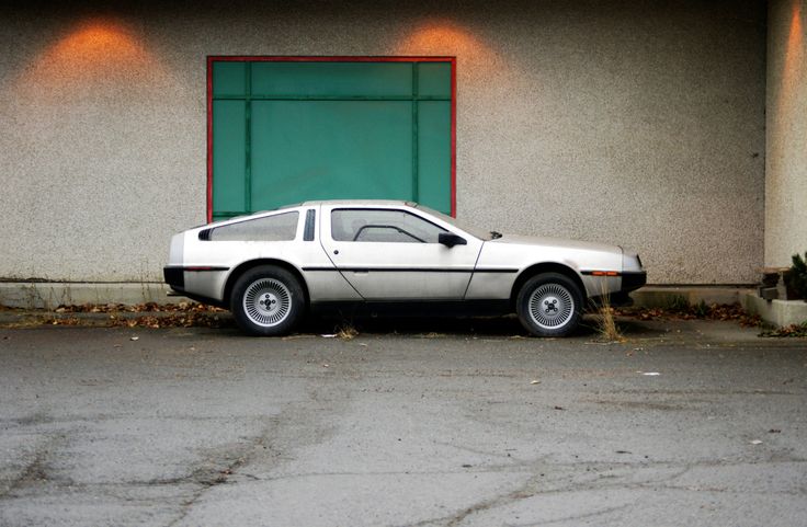 a white delore parked in front of a building next to a green door and window