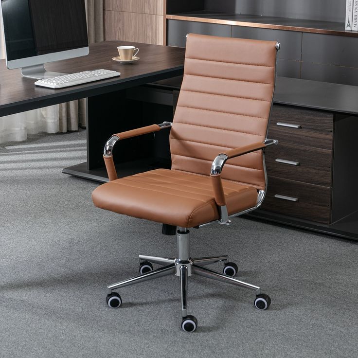 a brown office chair sitting in front of a desk with a computer monitor and keyboard