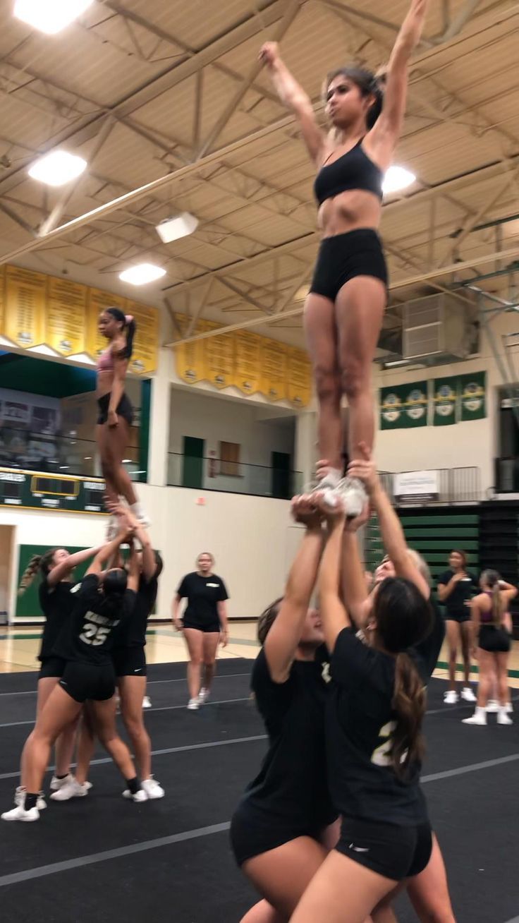 the cheerleaders are doing tricks for the girls on the basketball court as they hold their hands in the air