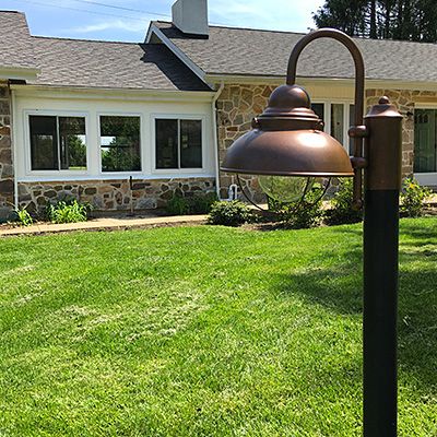 a lamp post in front of a house with grass and bushes on the lawn next to it