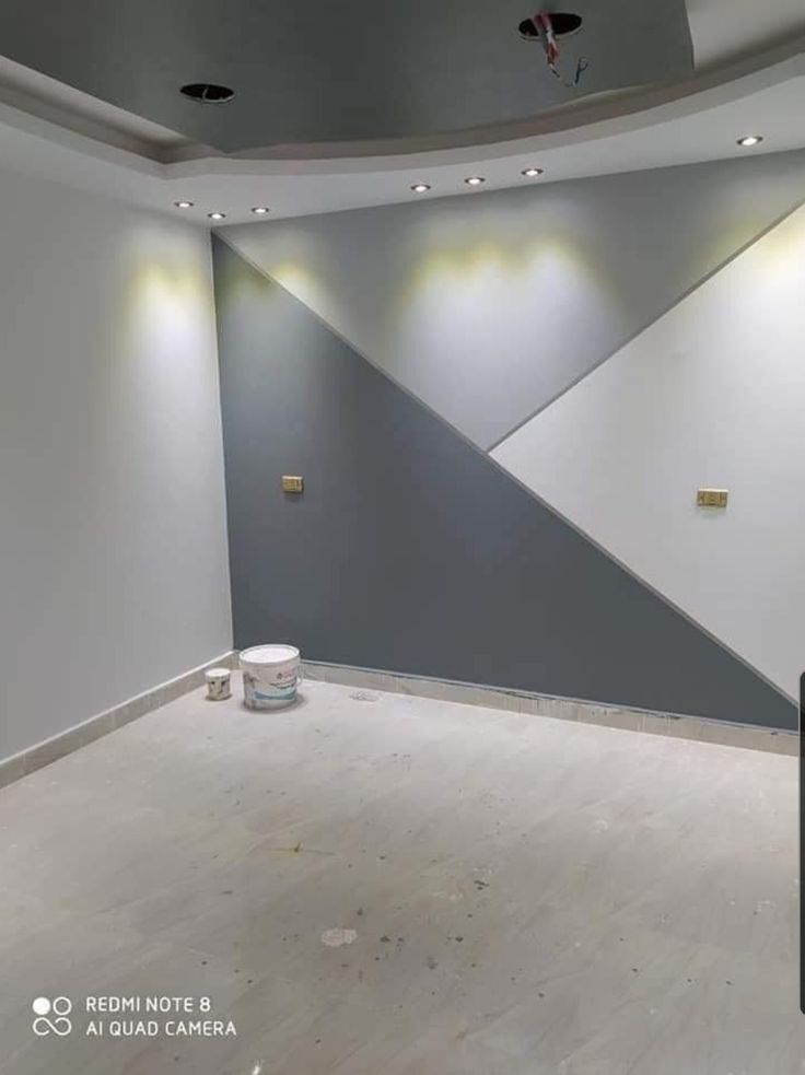 an empty room with some lights on the ceiling and a wall painted grey, white and gold