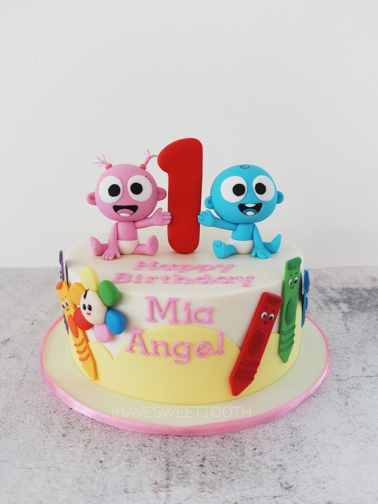 a birthday cake with the number one on it and two cartoon characters sitting at the top