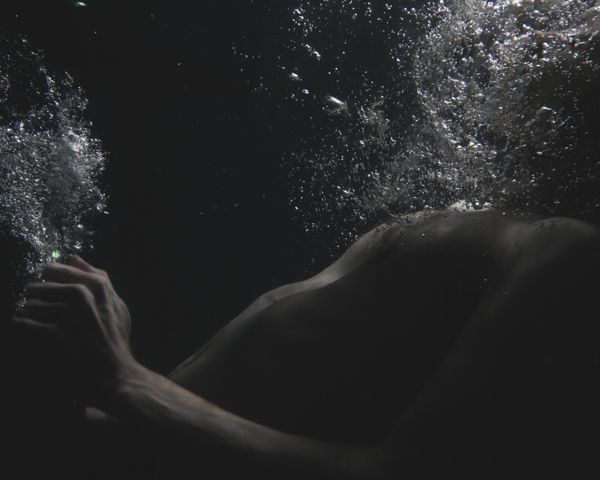 a man swimming in the water with his hand under his chin and face covered by bubbles