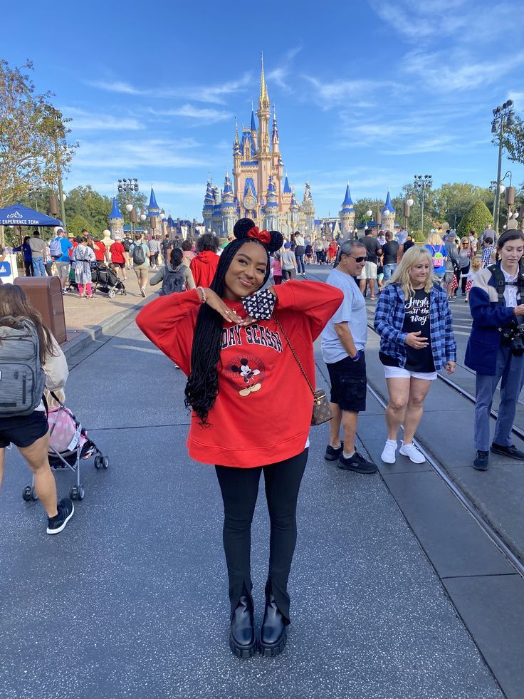 a woman standing in front of a castle with her hand on her head and people walking around