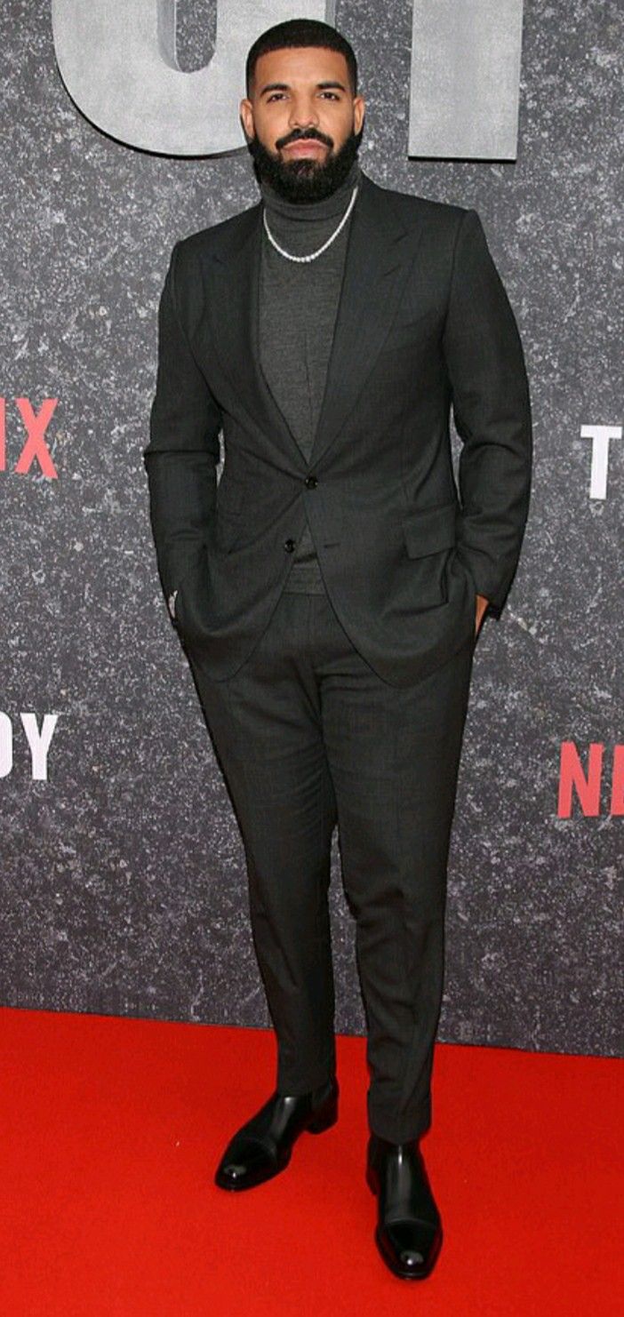 a man in a suit standing on a red carpet