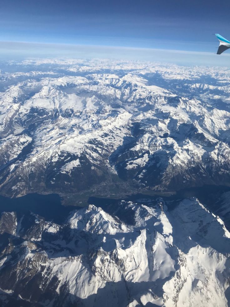 an airplane wing flying over snow covered mountains