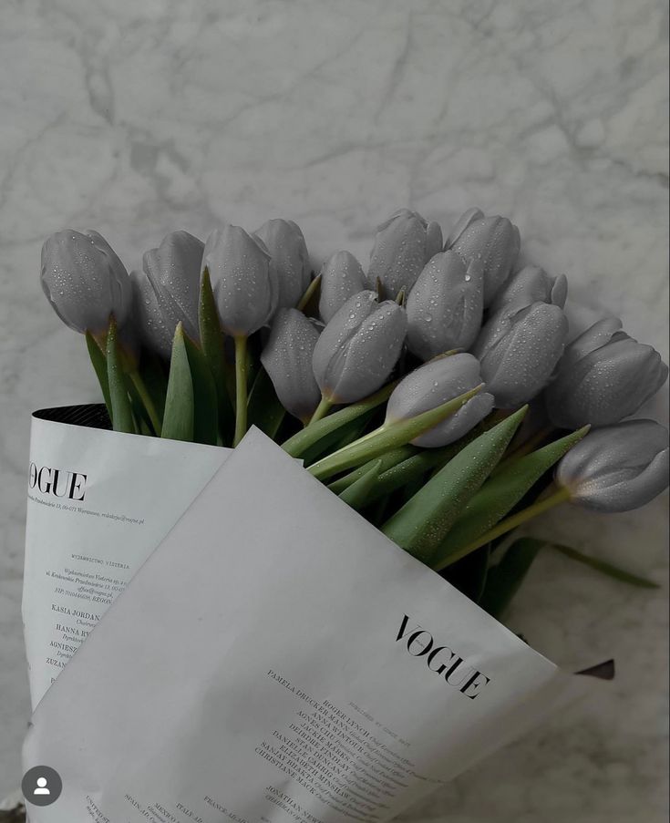 a bouquet of tulips sitting on top of a table next to a piece of paper