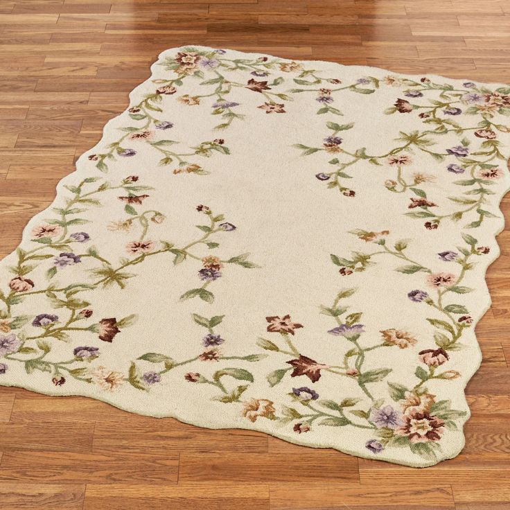 a white rug with flowers and leaves on the floor in a room that has wooden floors