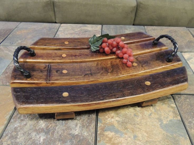 a wooden platter with grapes on it sitting on a tile floor next to a couch