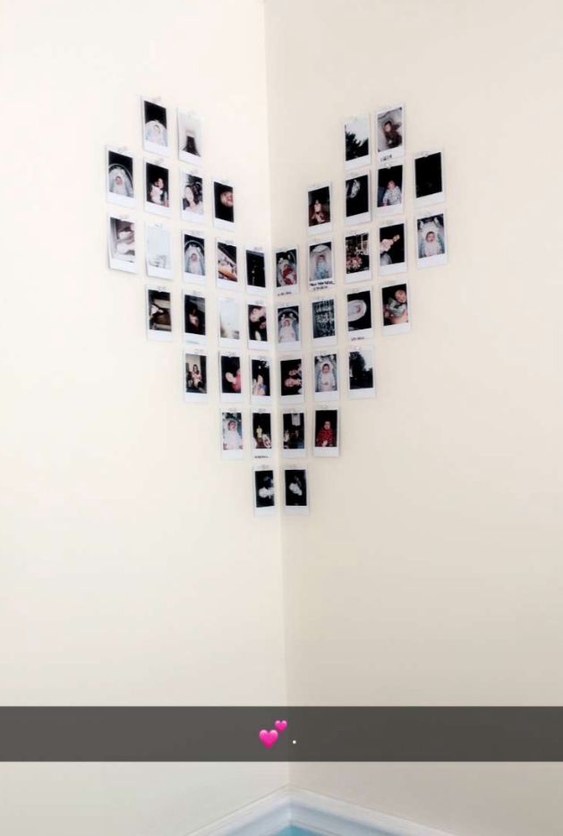 a heart shaped wall hanging on the side of a white wall with photos attached to it