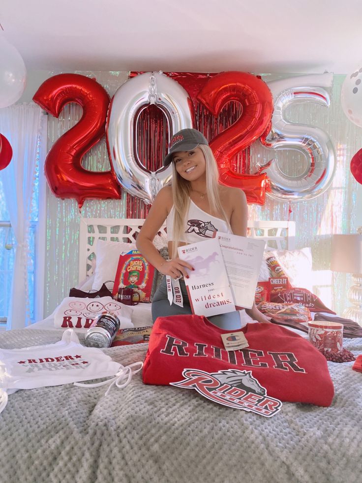 a woman standing on top of a bed in front of balloons and letters that spell out 2012