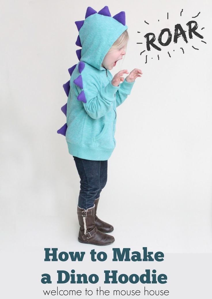 a young child wearing a dinosaur hoodie with the words roar written on it's back