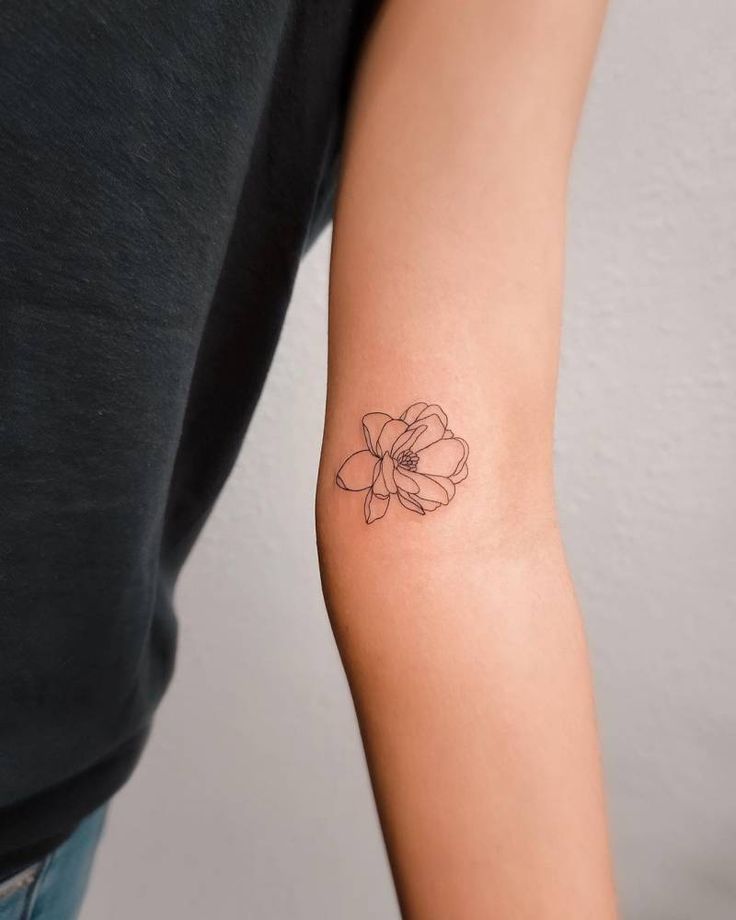 a woman's arm with a small flower tattoo on the left side of her arm