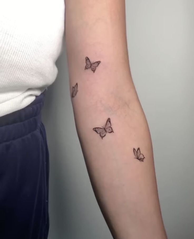 a woman's arm with three butterflies on the left side of her arm,