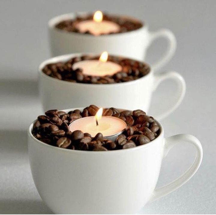 three cups filled with coffee beans and lit candles