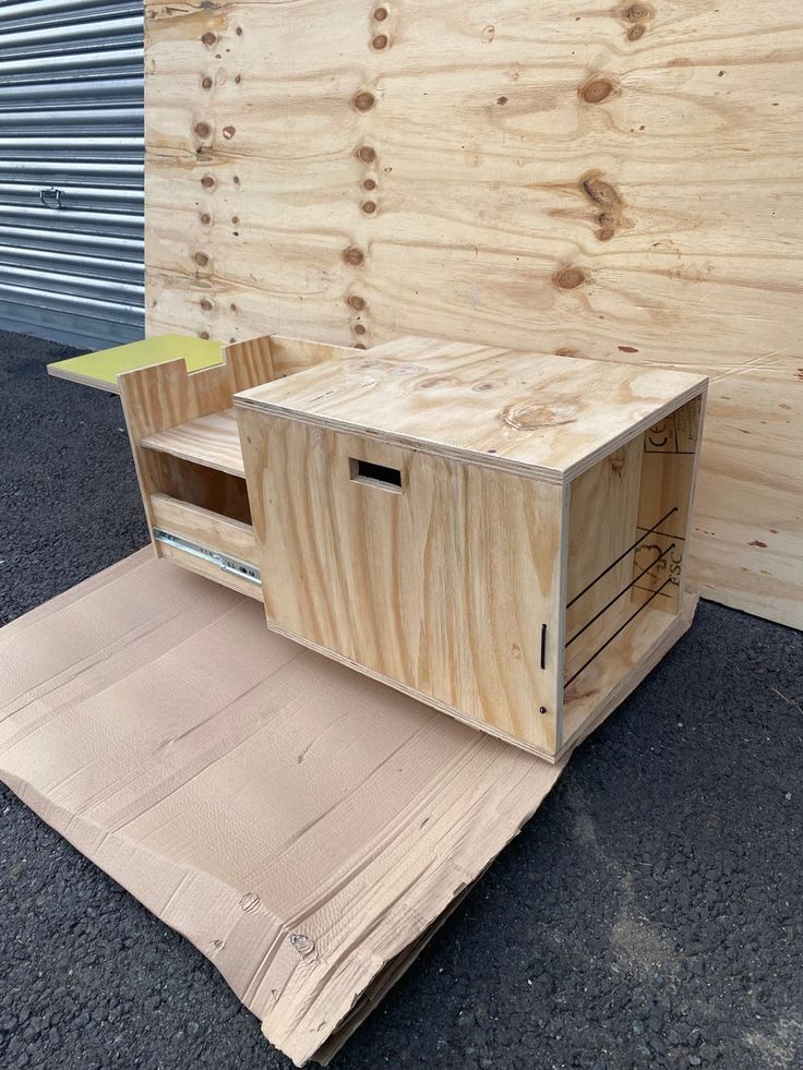 a wooden box sitting on top of a piece of plywood