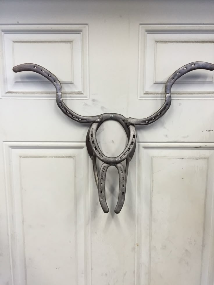 a pair of scissors hanging from the side of a door with horns attached to it