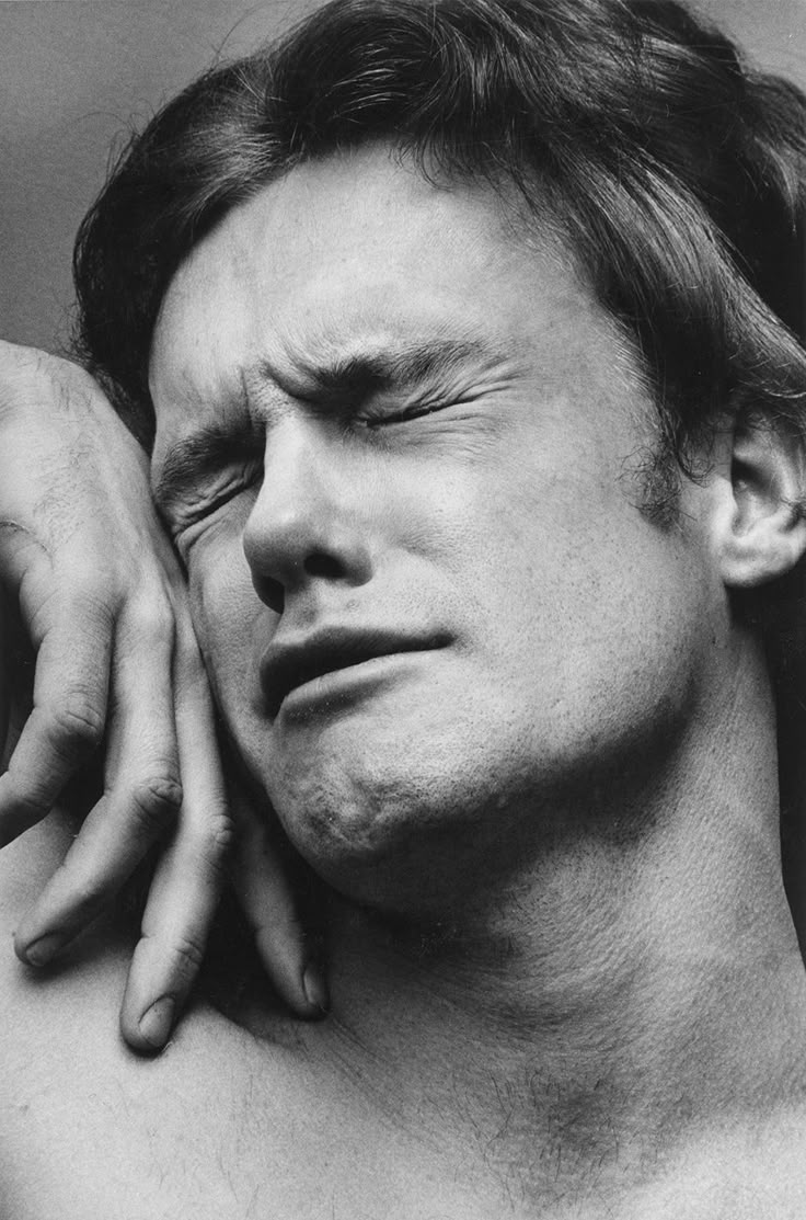 a black and white photo of a man with his hand on his shoulder looking to the side