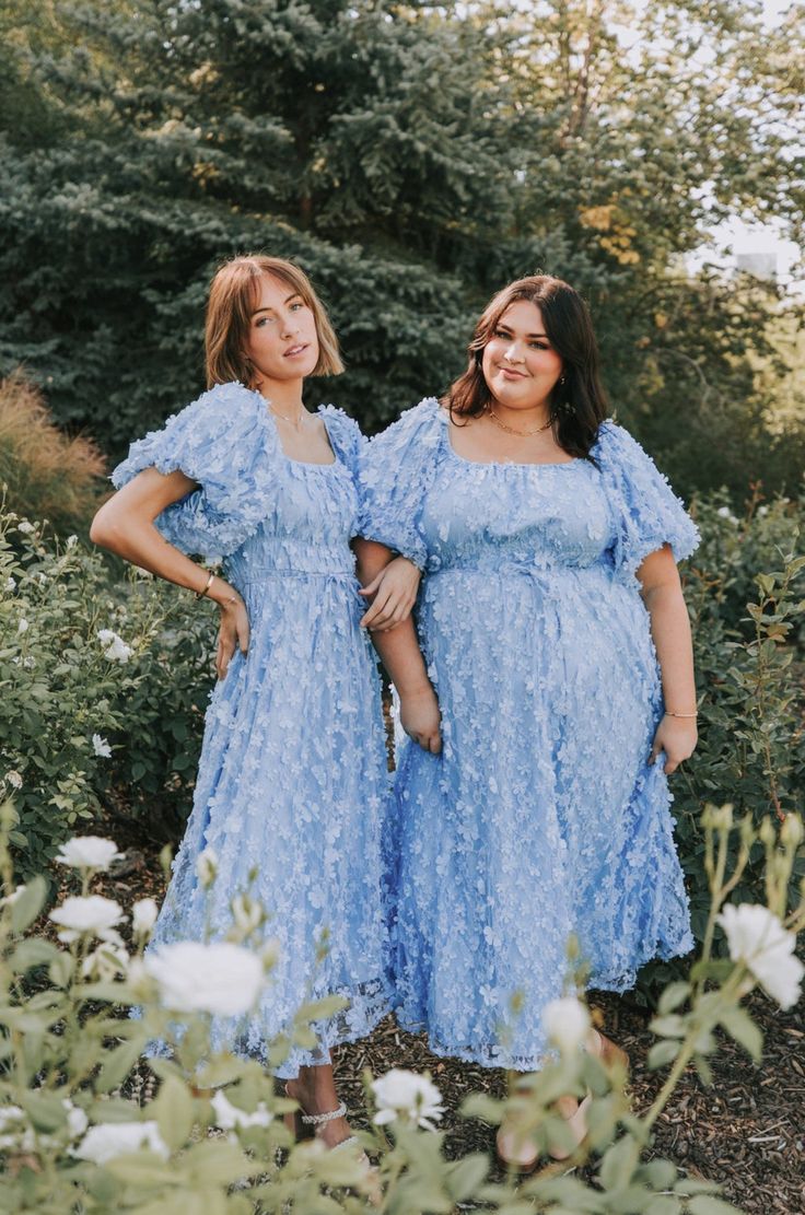 two women in blue dresses standing next to each other