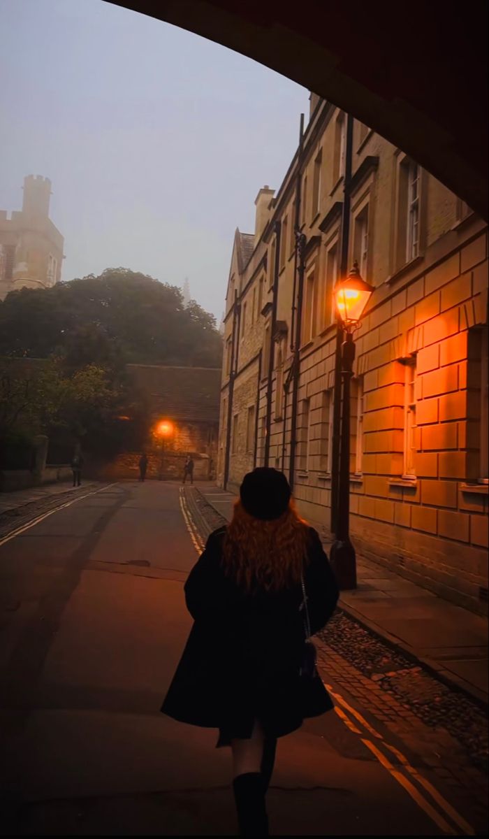 a woman is walking down the street at night