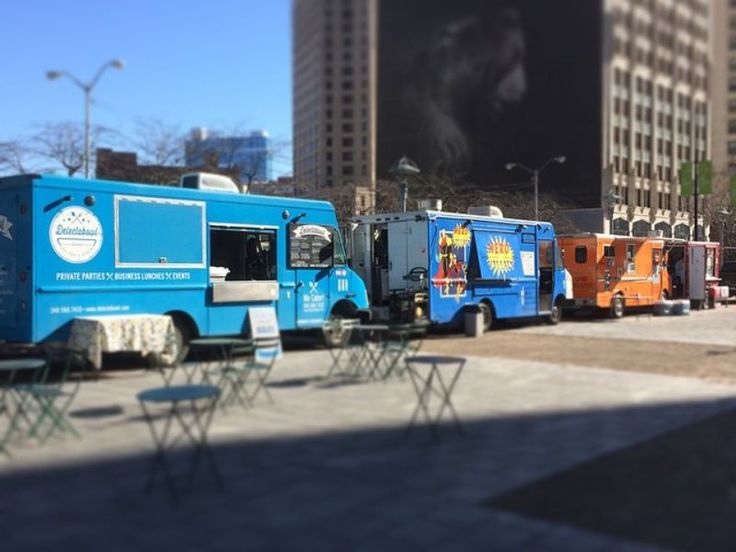 several food trucks are parked on the side of the road in front of tall buildings