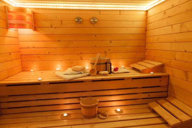 a wooden sauna with candles and towels on the floor next to it is lit up