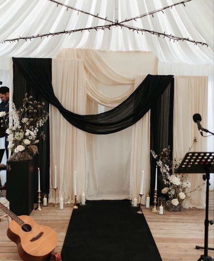 a black and white wedding ceremony setup with a guitar on the floor in front of it