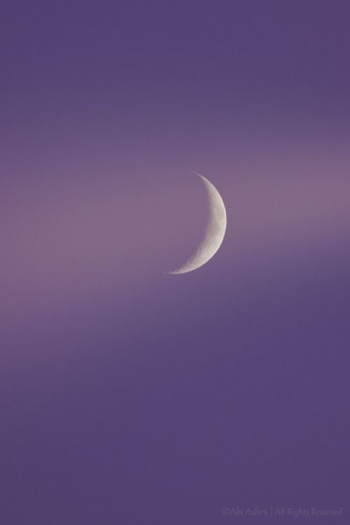 the moon is seen through some clouds on a purple sky with no one in it