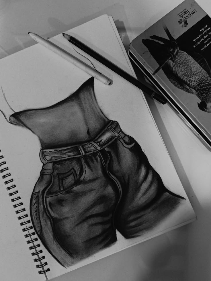 a pencil drawing of a pair of pants and a pen on top of a notebook