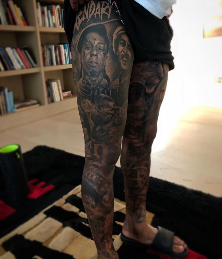 a man with tattoos on his legs and leg is standing in front of a book shelf