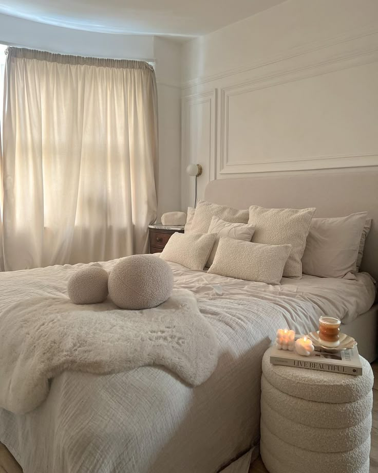 a bed with white sheets and pillows on top of it next to a window filled with curtains