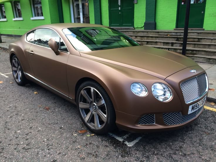 a brown car parked in front of a green building with steps leading up to it