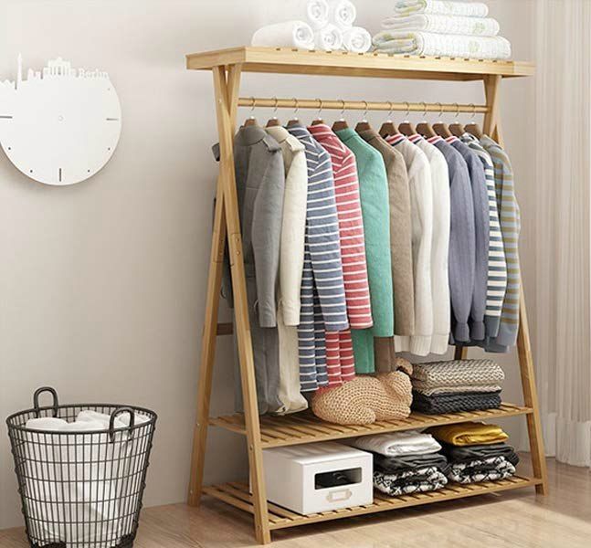 a rack with clothes and baskets on it in front of a wall clock, next to a basket