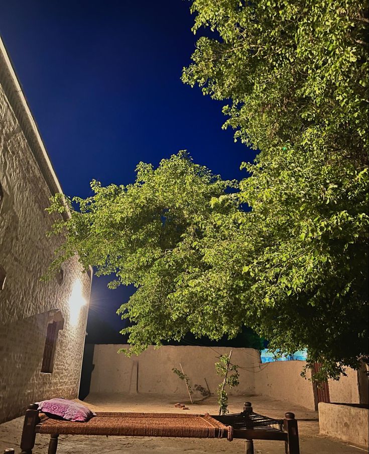 a bench sitting in the middle of a sidewalk next to a tree and some buildings