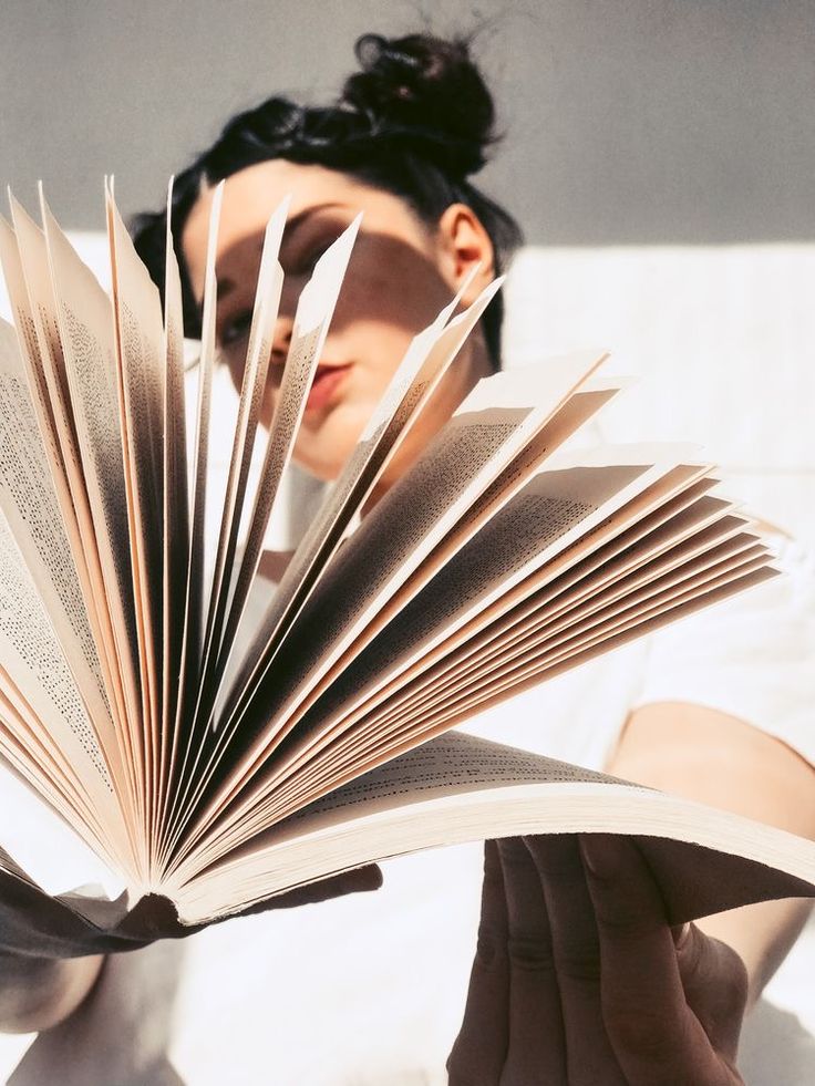 a woman is holding an open book in her hands