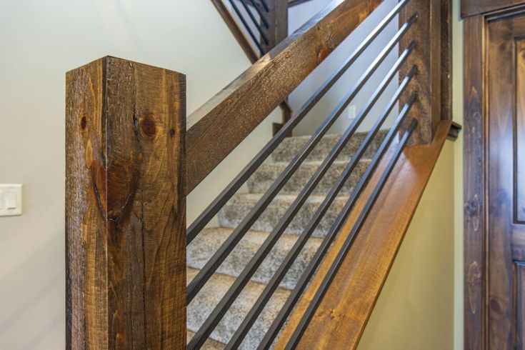 a wooden stair case with metal handrails next to a door and light fixture