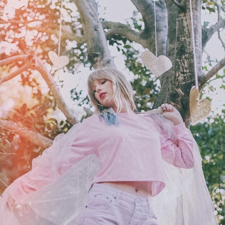 a woman standing in front of a tree with hearts hanging from it