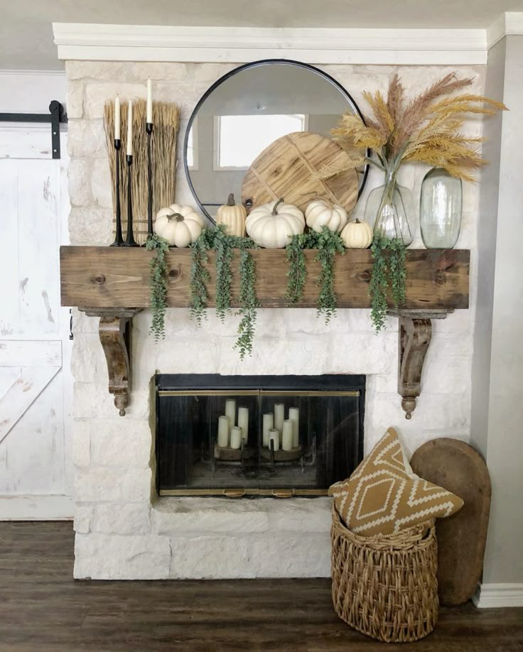 the fireplace is decorated with white pumpkins, greenery and other things on it