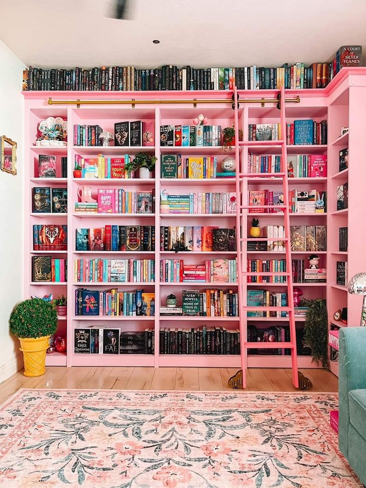 a pink book shelf filled with lots of books next to a blue couch and rug