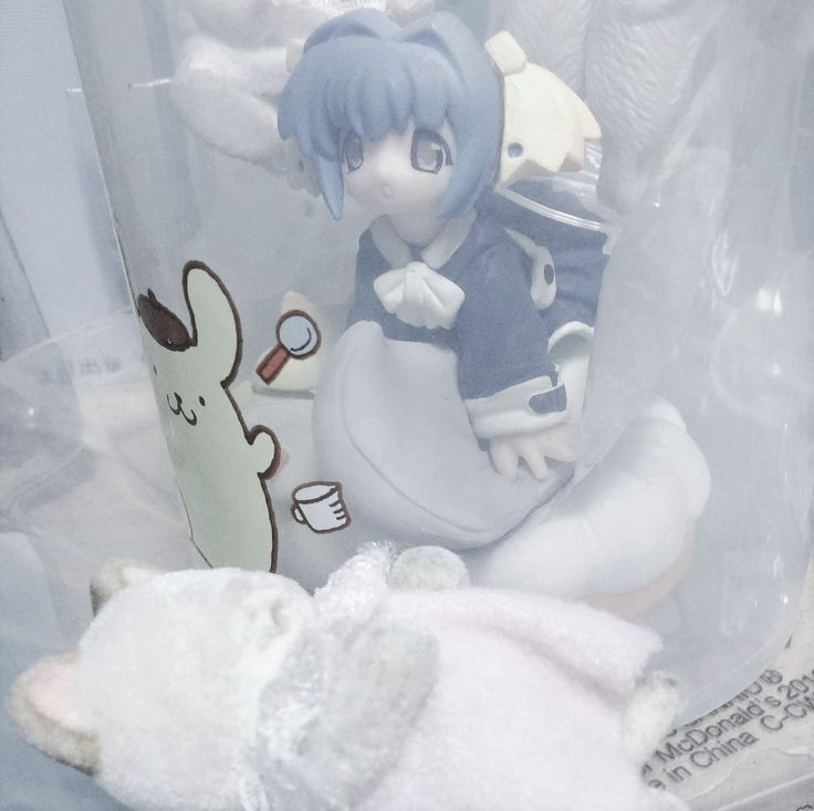 an anime figurine sitting next to a stuffed animal