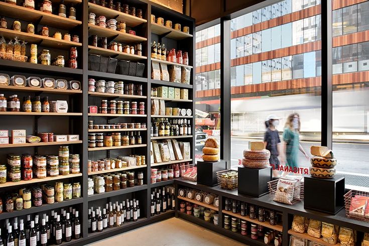 two people are walking through a store with shelves full of food