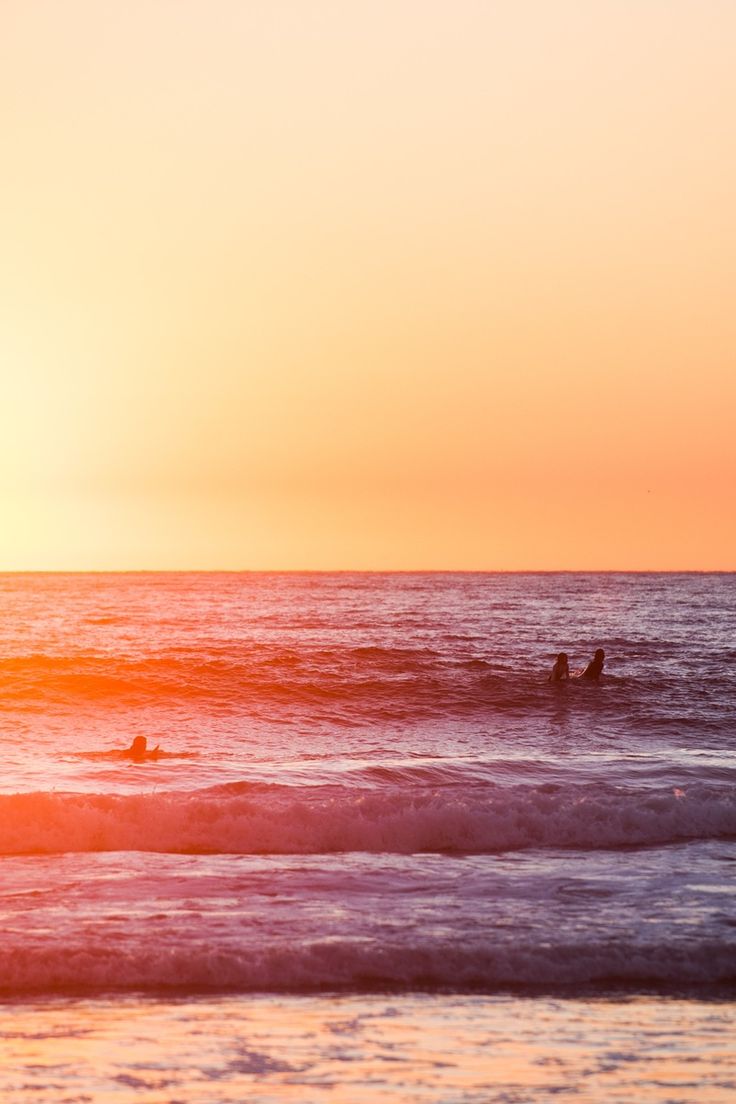 two surfers in the ocean at sunset