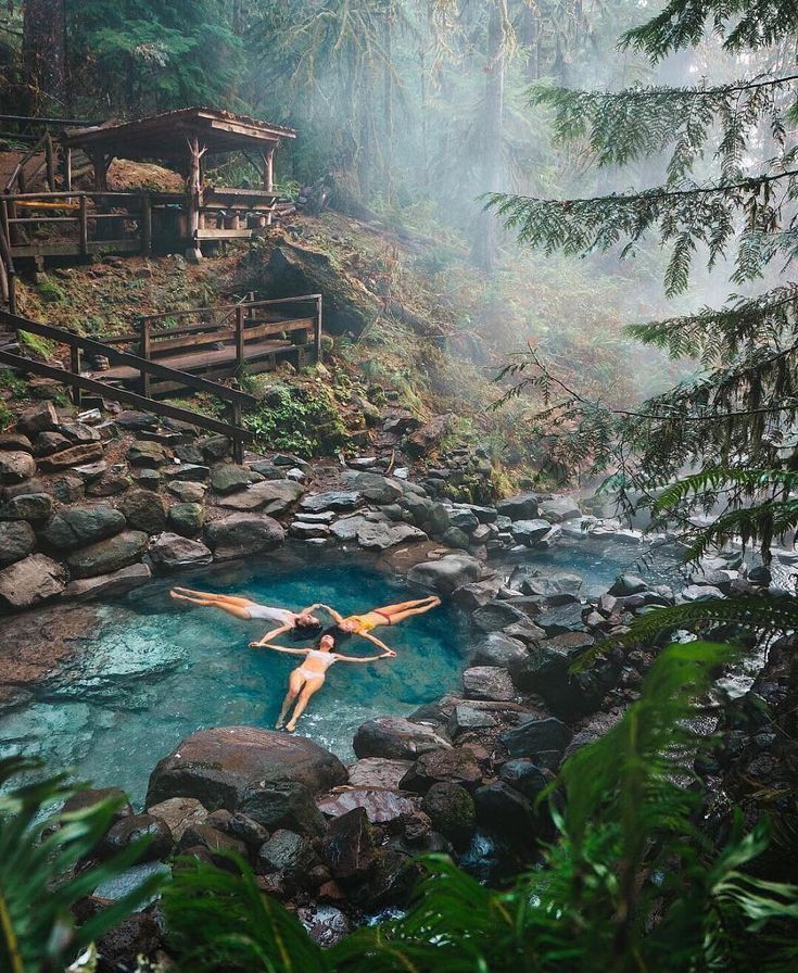 a woman floating in a hot spring surrounded by trees