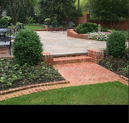 a brick patio surrounded by trees and bushes